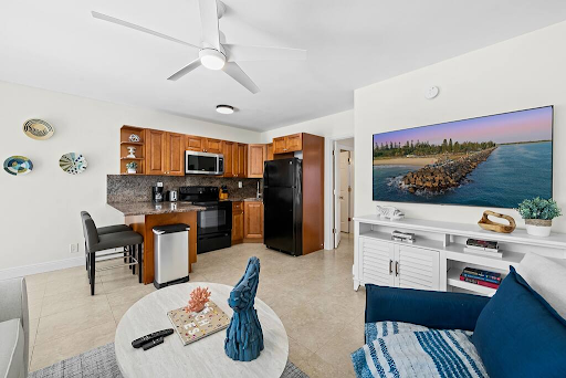 A living room filled with furniture and a kitchen with a ceiling fan.