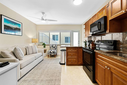 A living room with a couch and a kitchen with a stove and microwave.