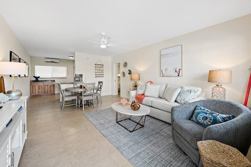 A living room with a couch , chair , table and ceiling fan.