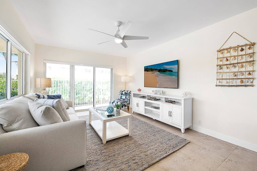 A living room with a couch , coffee table , television and ceiling fan.