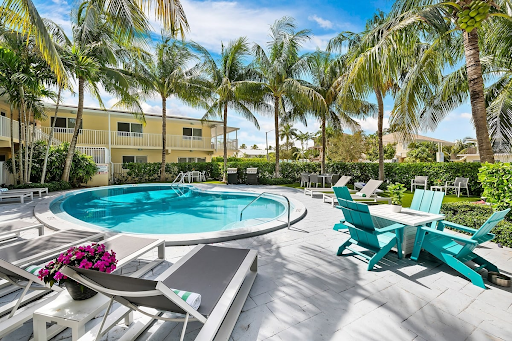 A large swimming pool surrounded by chairs and palm trees.
