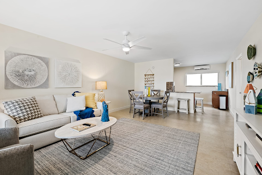 A living room with a couch , coffee table , chairs and a ceiling fan.