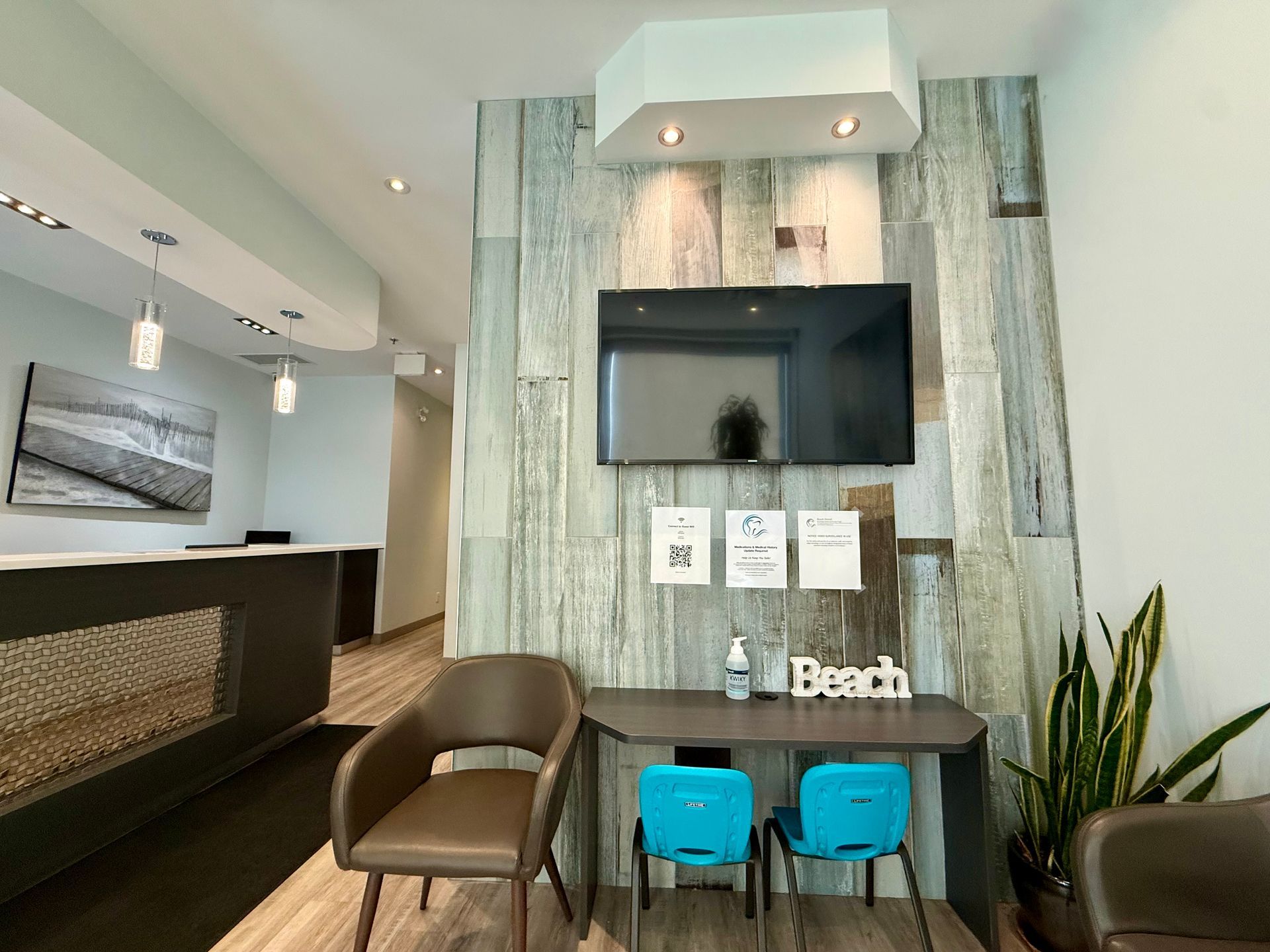 Modern lobby with TV wall, desk, turquoise stools, chairs, and potted plants