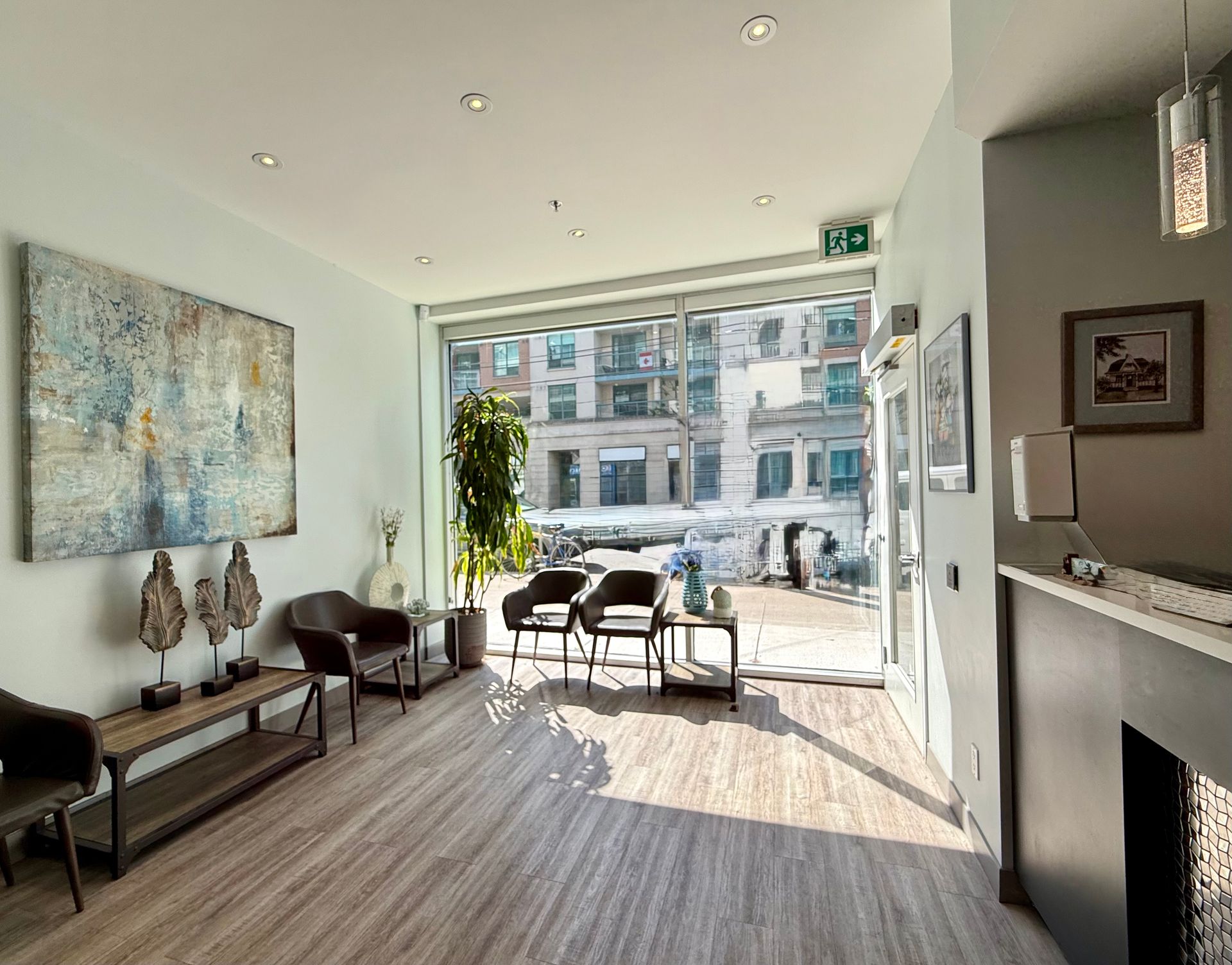 Bright modern living room with floor-to-ceiling windows, neutral furniture, artwork, and city view.