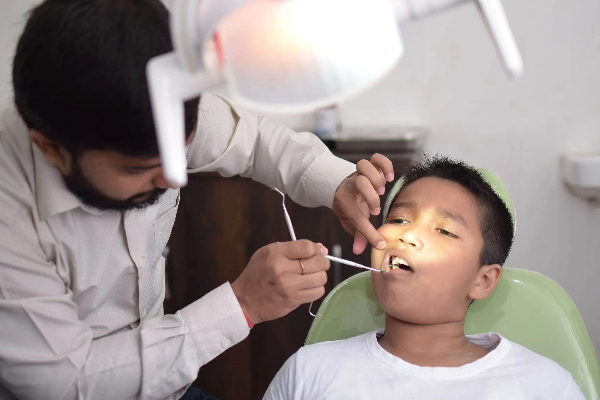 Dentist examining a child’s teeth in a bright clinic chair