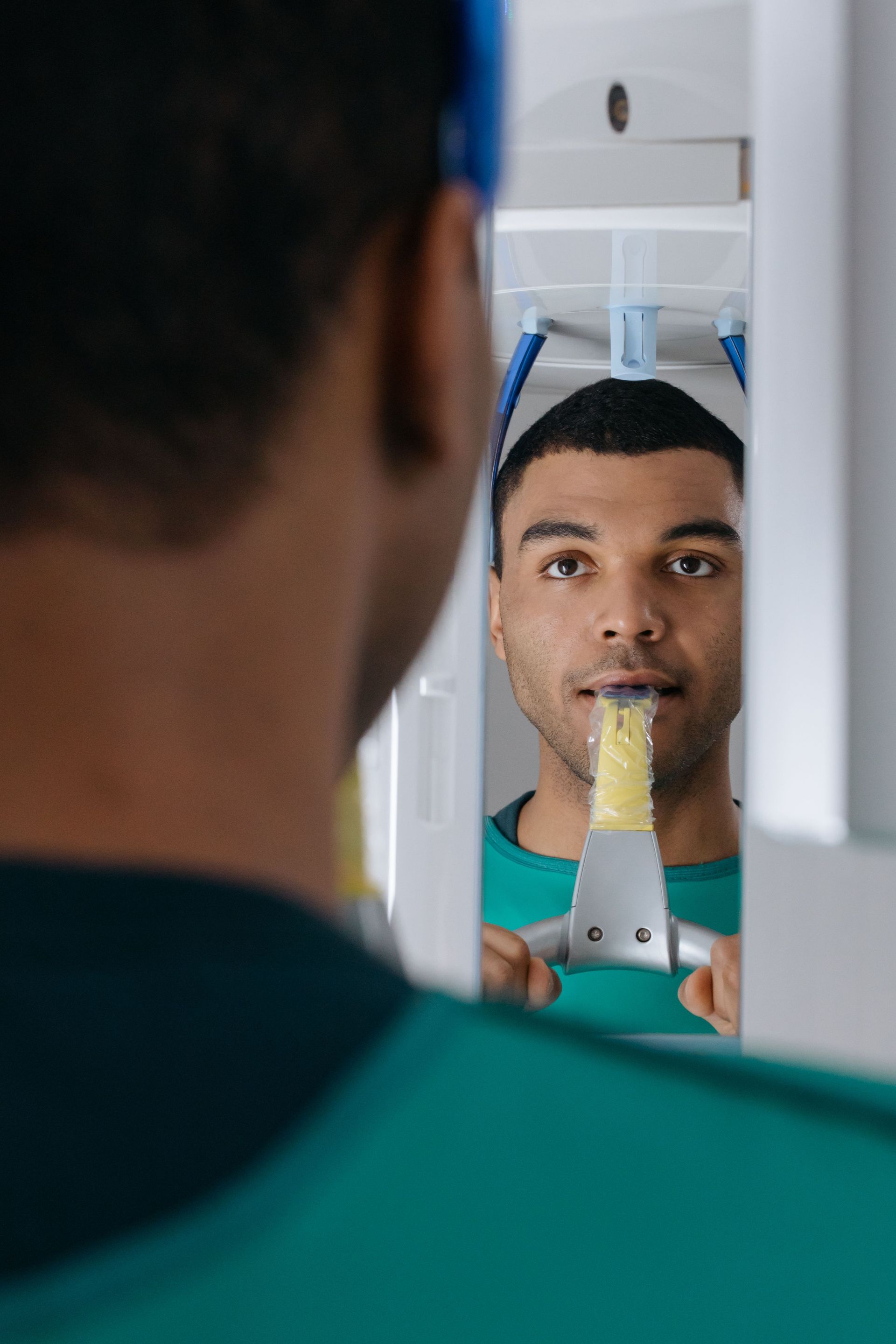 Man looking at himself in a mirror while trimming a mustache with an electric trimmer