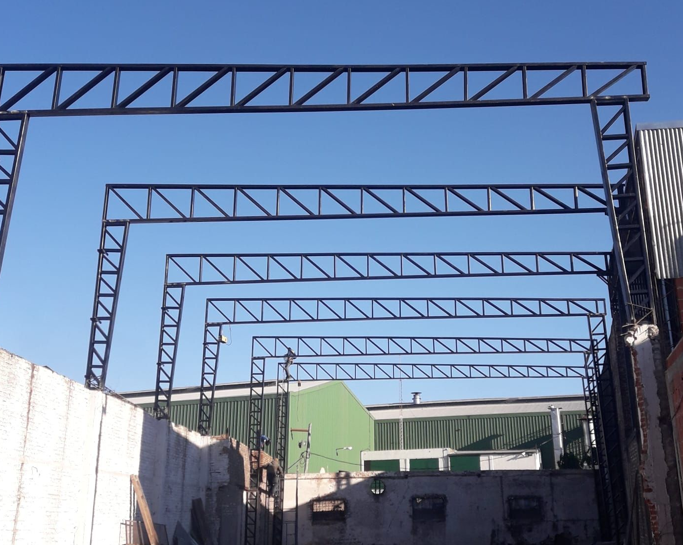Estructura de armazón metálico contra un cielo azul, que se extiende a lo largo del tejado de un edificio.