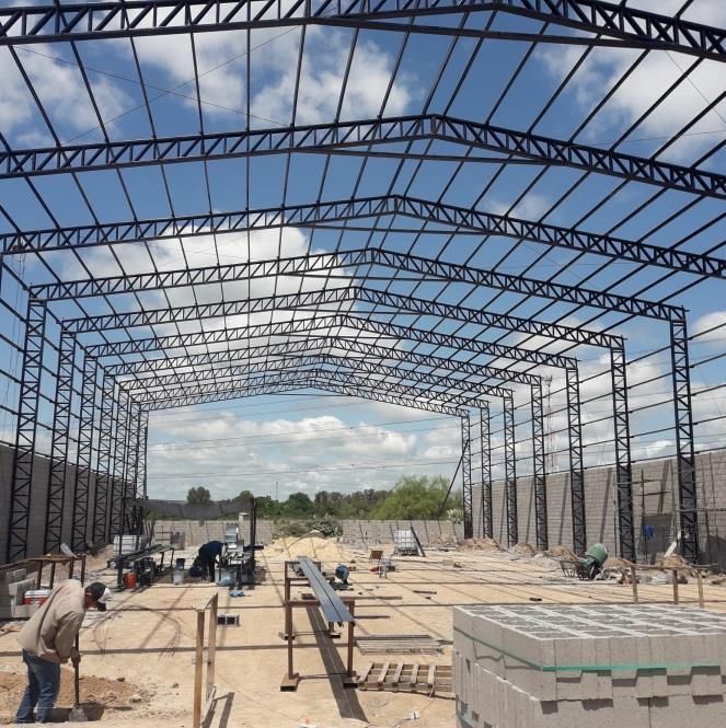 Estructura metálica de un edificio en construcción, obreros en la obra. Cielo despejado