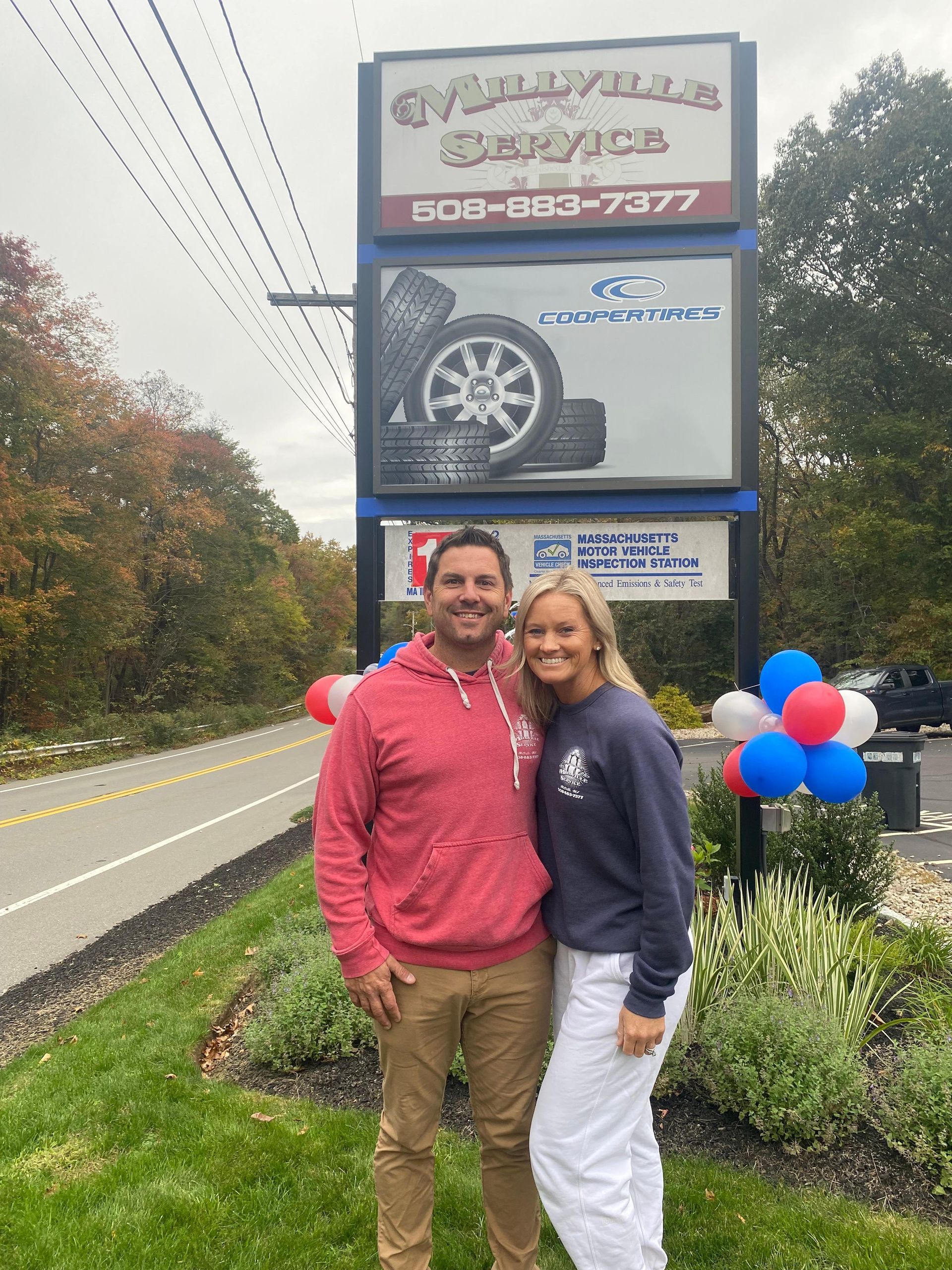 Owner And Customer Smiling In Front Of Shop Sign | Millville Service