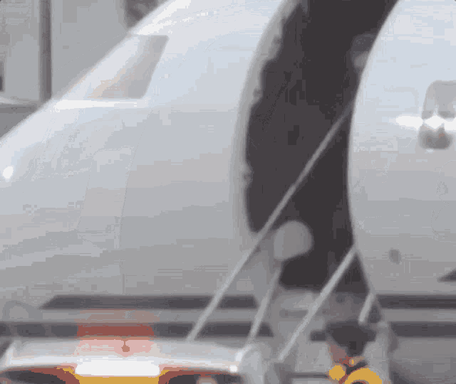 A person in yellow unloading luggage from a white airplane.