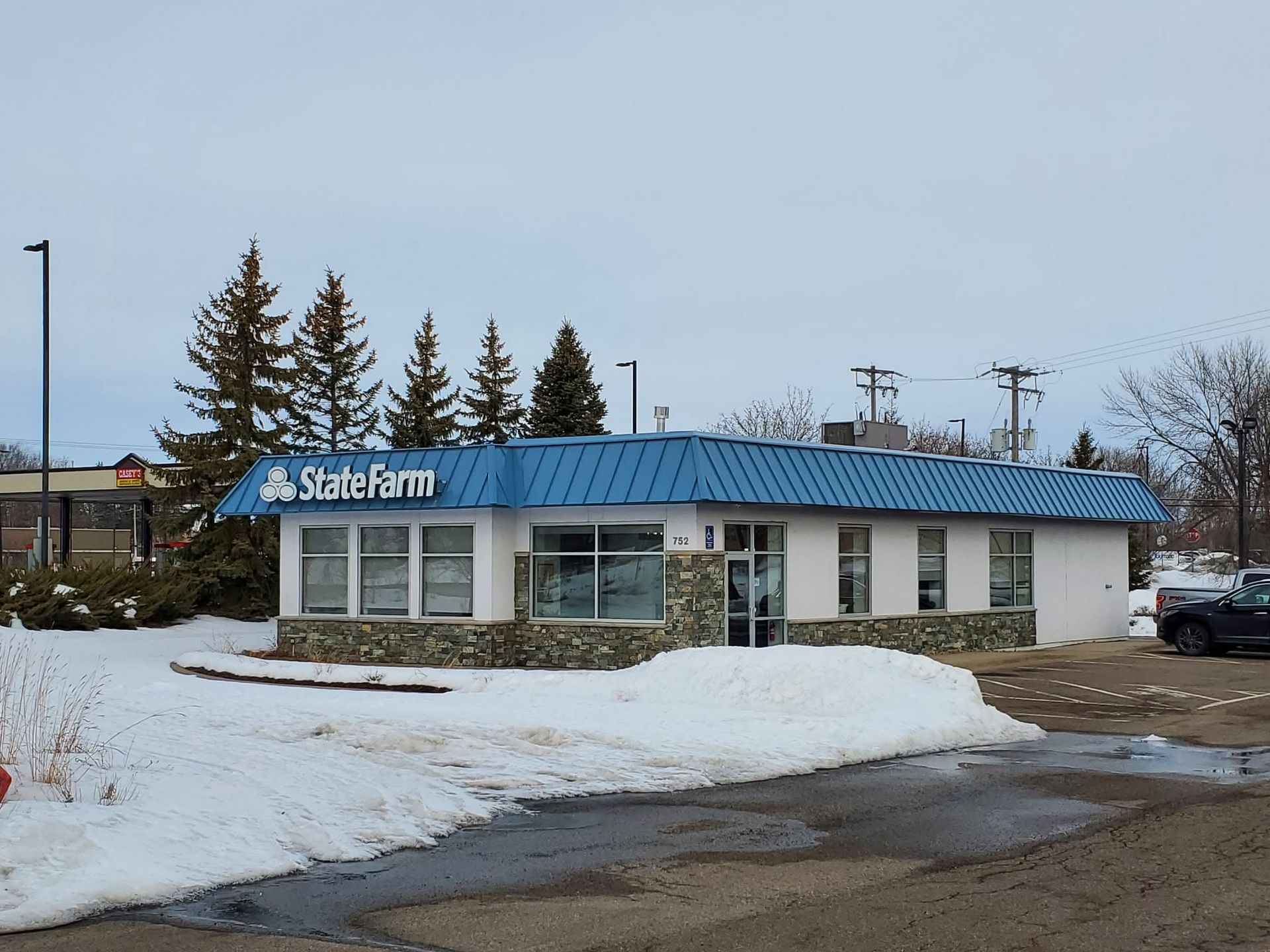 Small roadside building with blue roof and snowy ground on a winter day