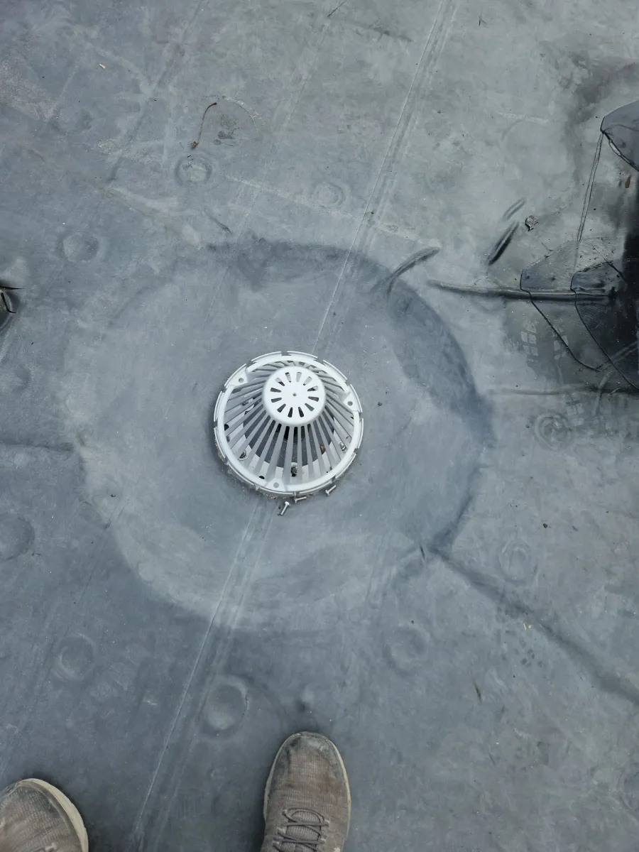 Gray rooftop with a circular vent and a person’s shoes at the bottom edge