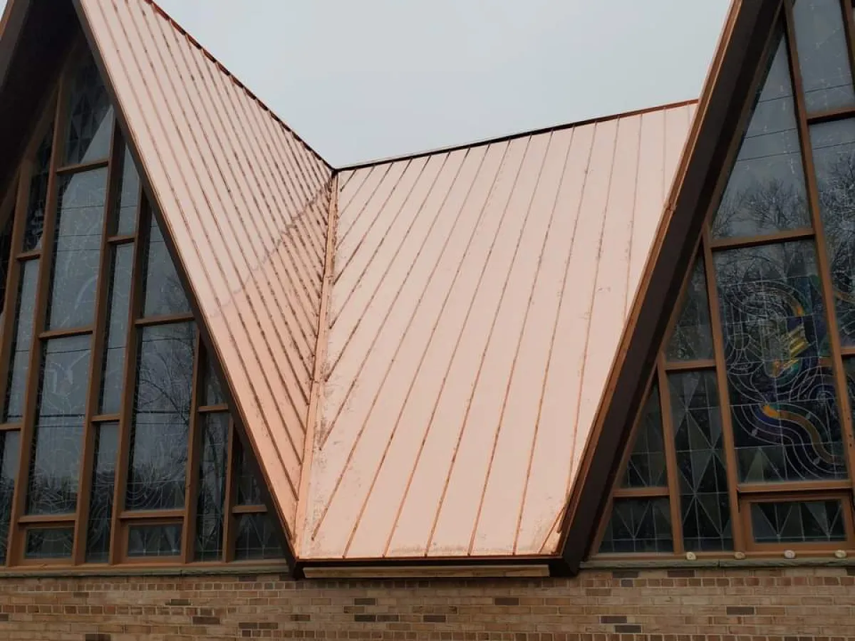 Copper-roofed modern building with tall triangular glass windows and a central V-shaped facade