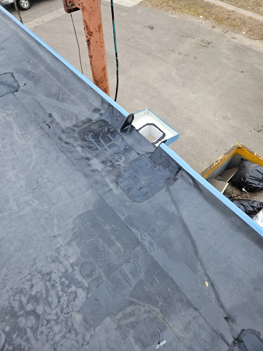 Rooftop edge with blue trim and a small white vent or light near a concrete wall.