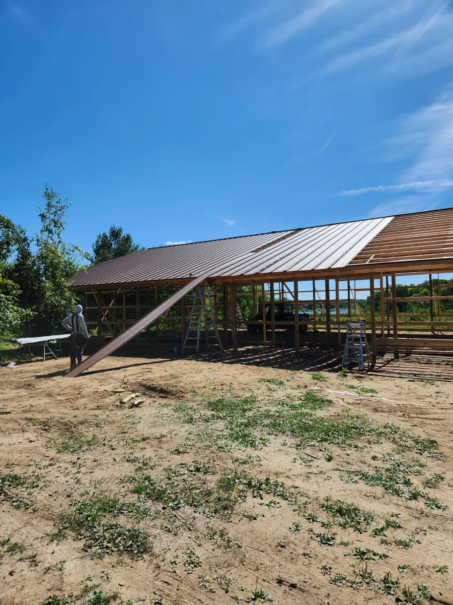Partially built wooden roof structure on a sandy lot under a bright blue sky