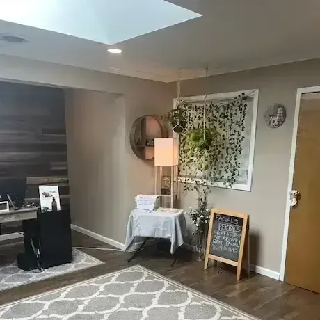 Cozy living room with patterned rug, lamp, side table, wall art, and chalkboard sign near a doorway