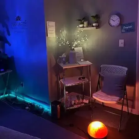 Cozy corner with blue and warm lighting, small desk, chair, wall clock, and glowing floor lamp.