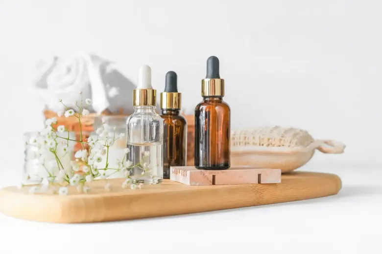 Spa products and wooden brush on a tray with dried flowers and amber glass bottles