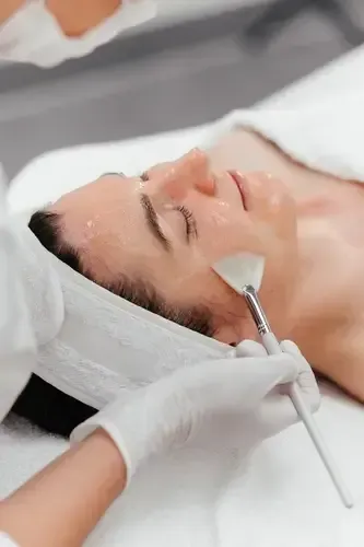 Spa facial treatment with a masked therapist applying a metal tool to a relaxed client's face