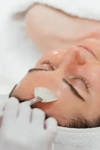 Gloved hand applies a facial mask to a person lying back with eyes closed
