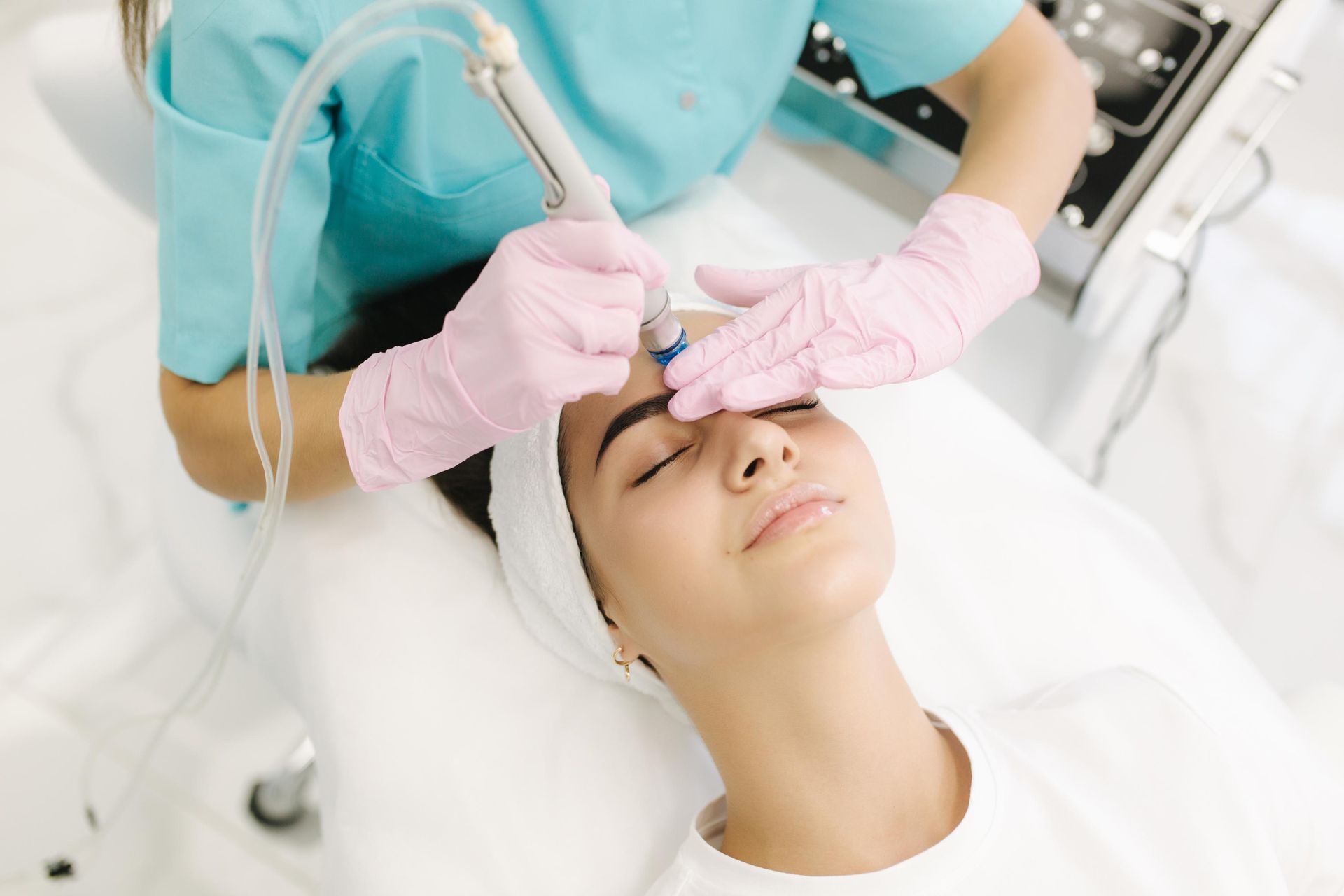 Aesthetic facial treatment with gloved hands using a handheld device on a relaxed patient