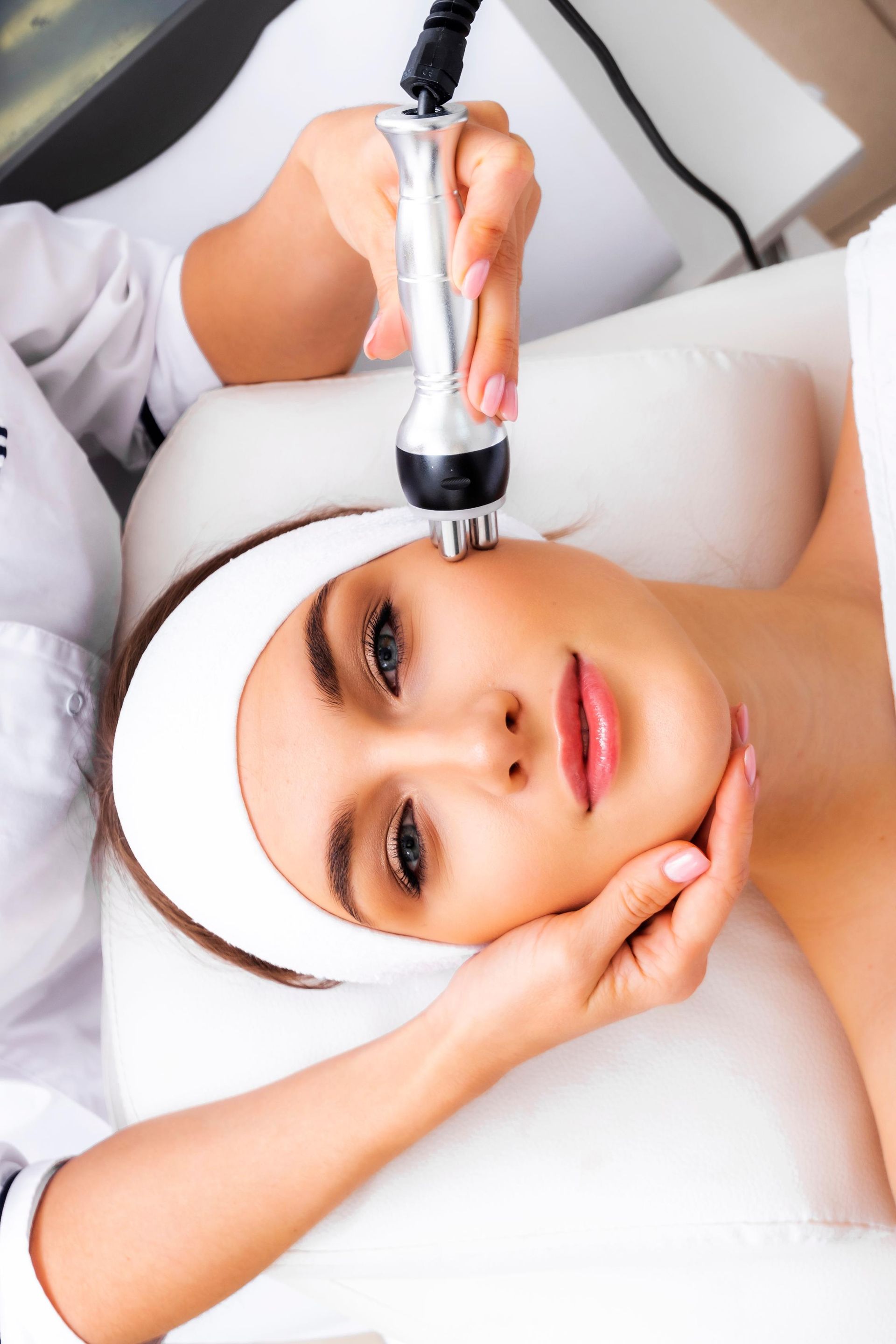 Woman receiving a facial treatment with a handheld device at a spa clinic
