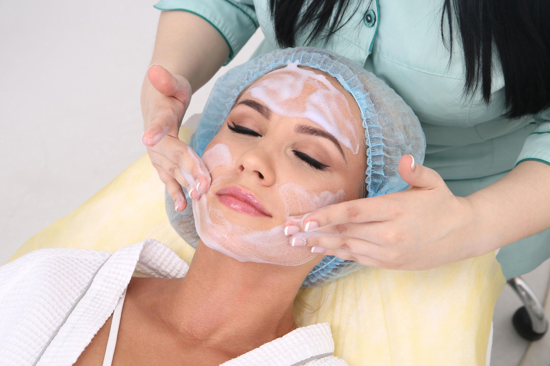 Facial treatment with cream being applied to a woman lying on a spa bed