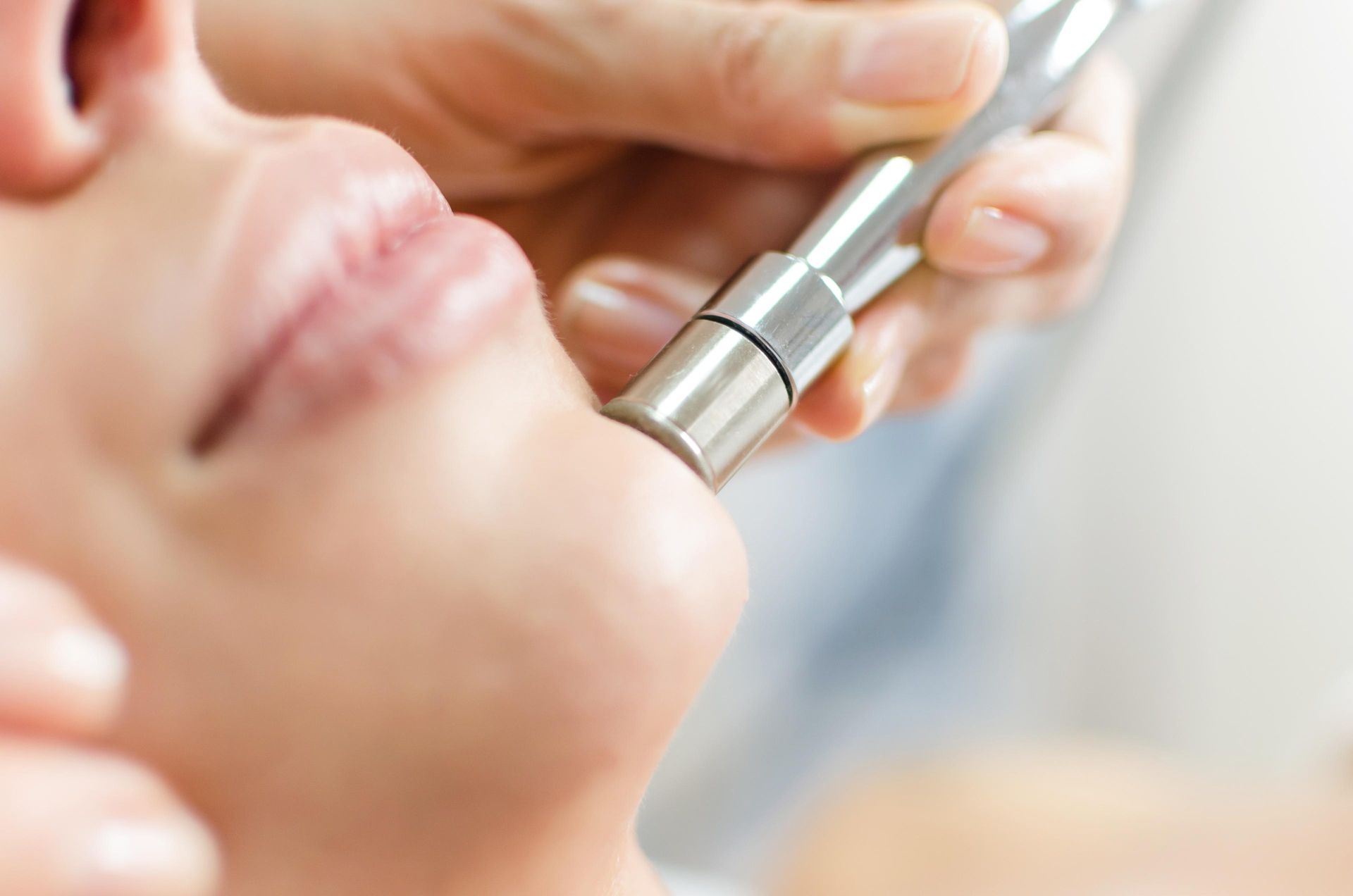 Close-up of a person receiving facial treatment with a handheld beauty device