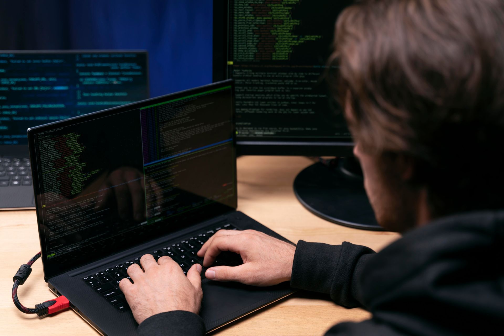 Um homem está digitando em um notebook enquanto está sentado em uma mesa.