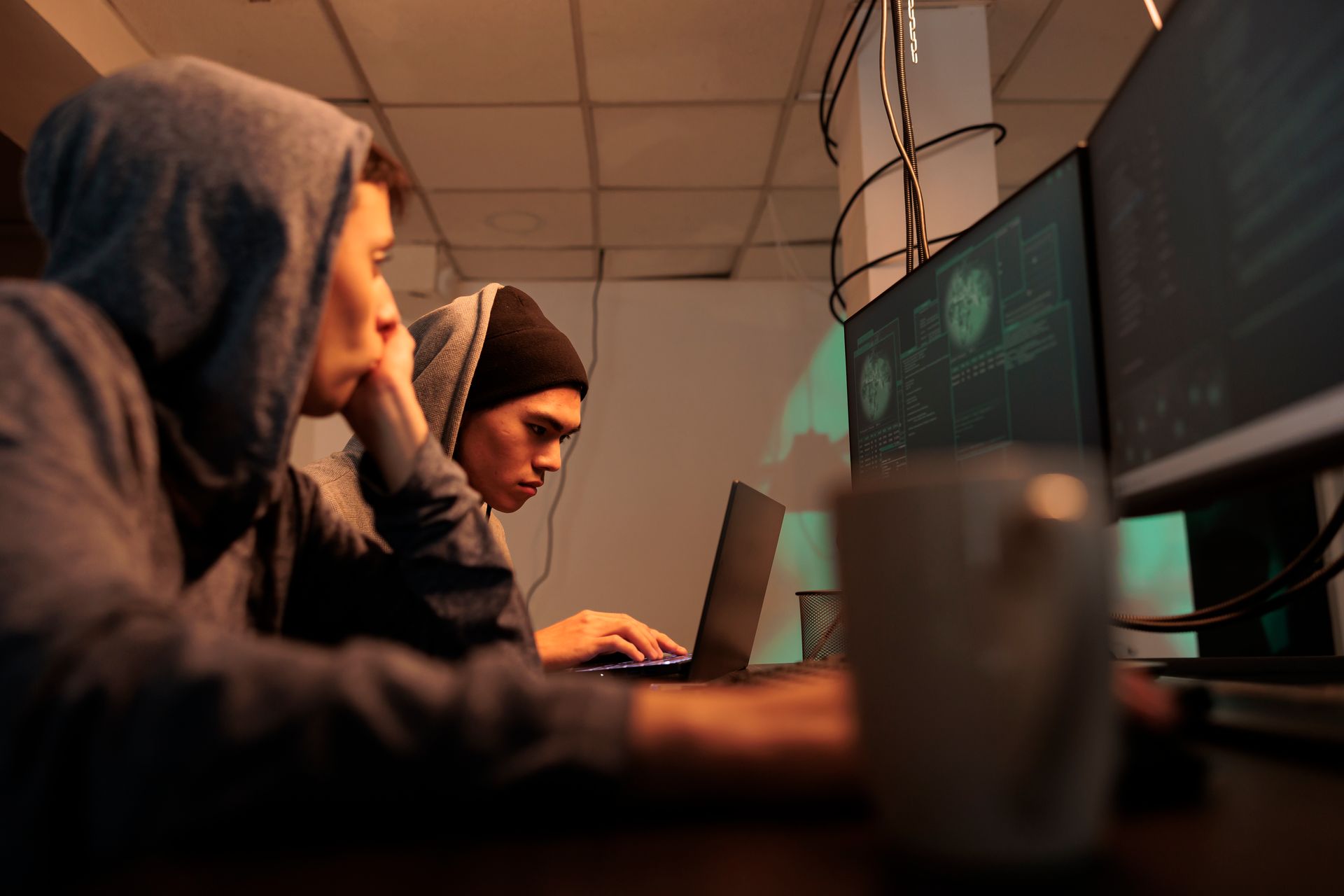 Um hacker sentado em frente a um computador em um quarto escuro