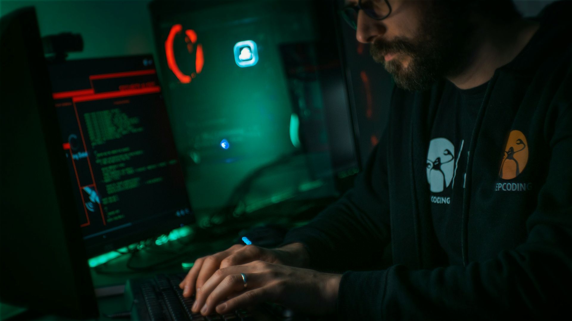 A man is sitting in front of a laptop computer in a dark room.