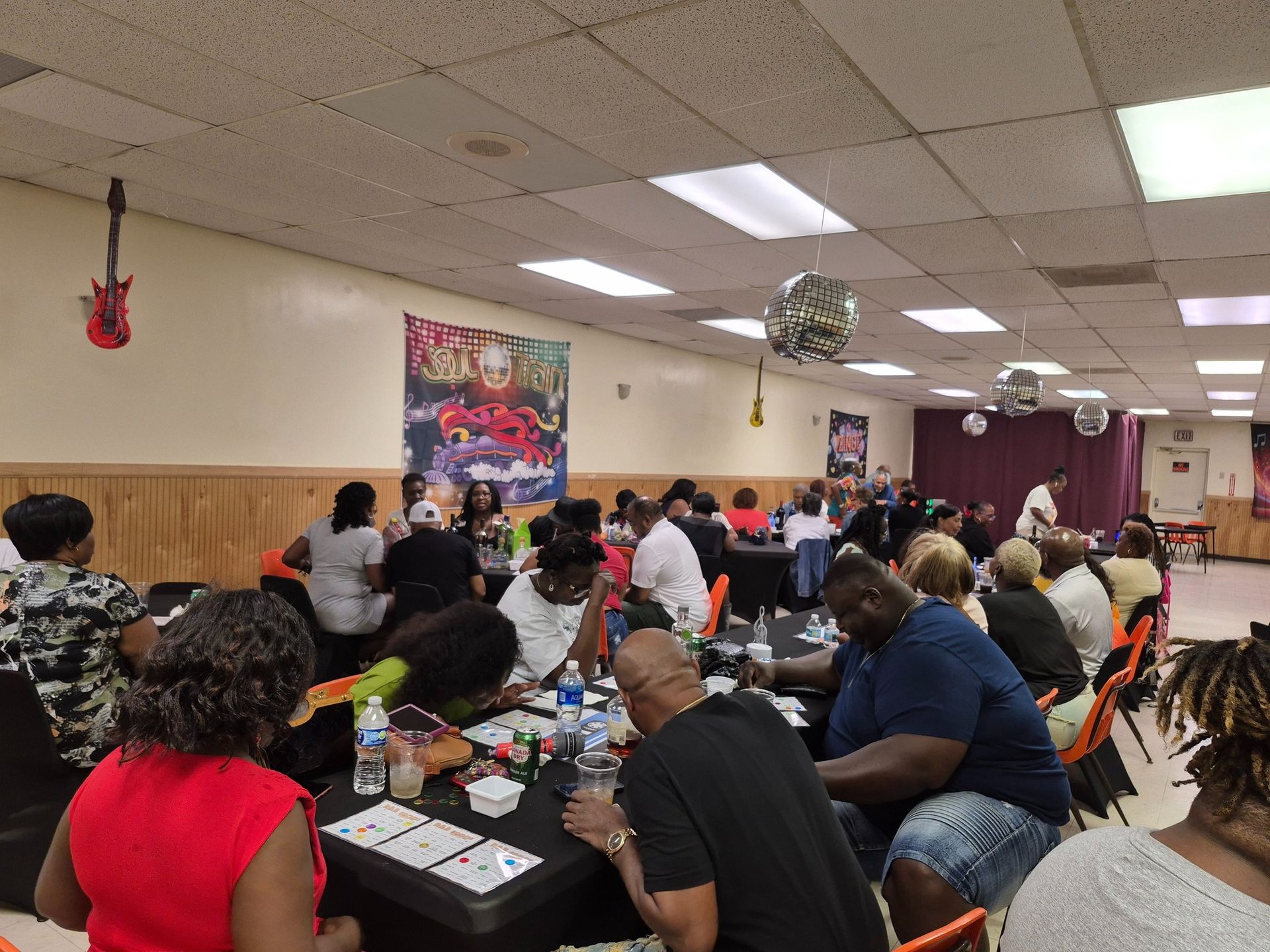 People at tables in a brightly lit room with decor, playing a game.