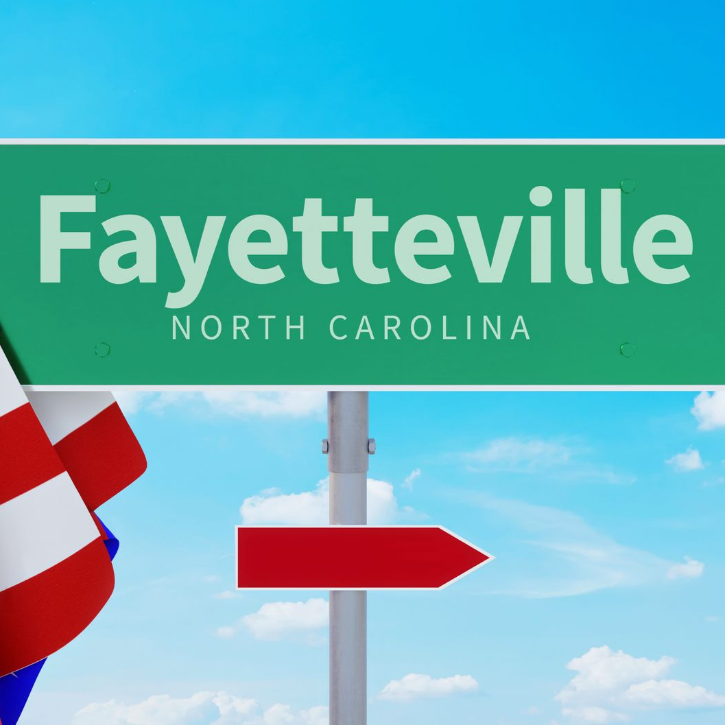 Fayetteville, North Carolina road sign with blue sky and a red directional arrow