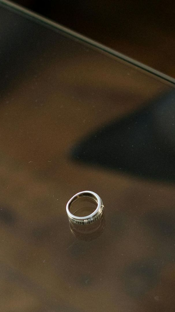 A wedding ring is sitting on a glass table.