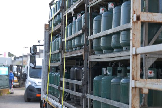 Camion che trasporta bombole di gas grigio impilate nel piazzale di un magazzino.