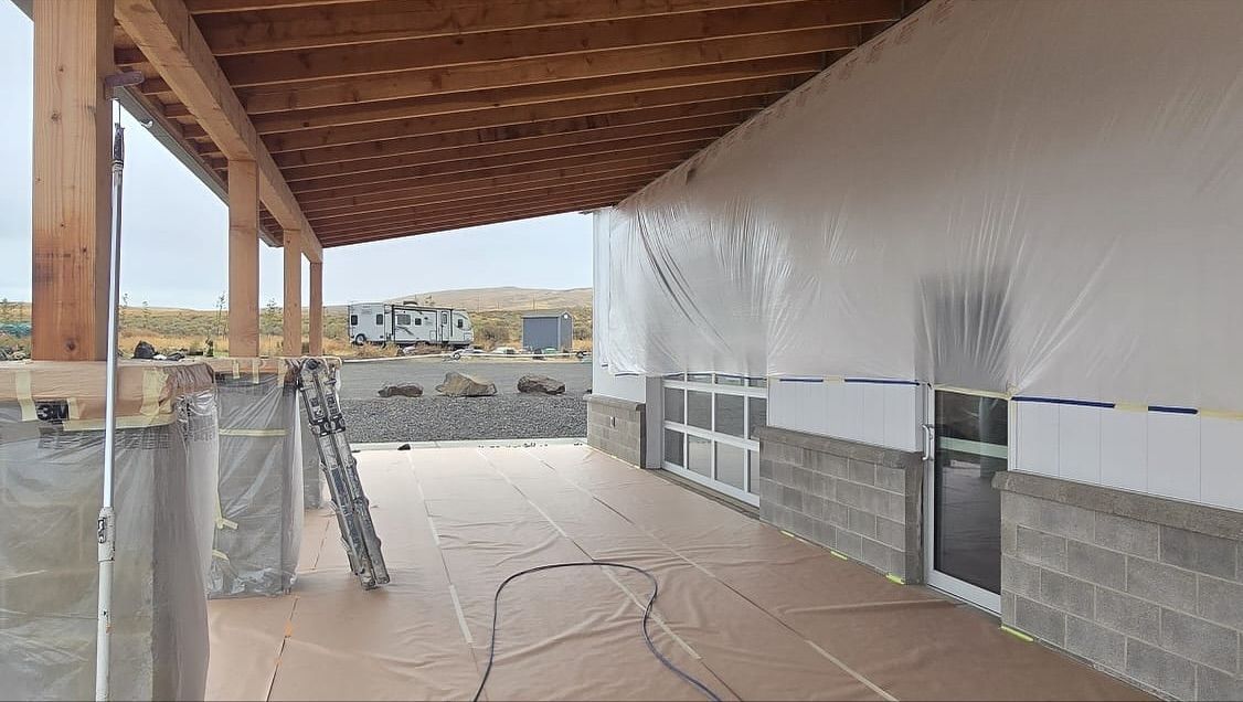 Stone outdoor pavilion with a dark wooden roof, built-in grill, and bench seating.