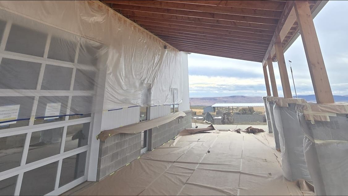 A building with glass garage doors and a wooden porch under construction.