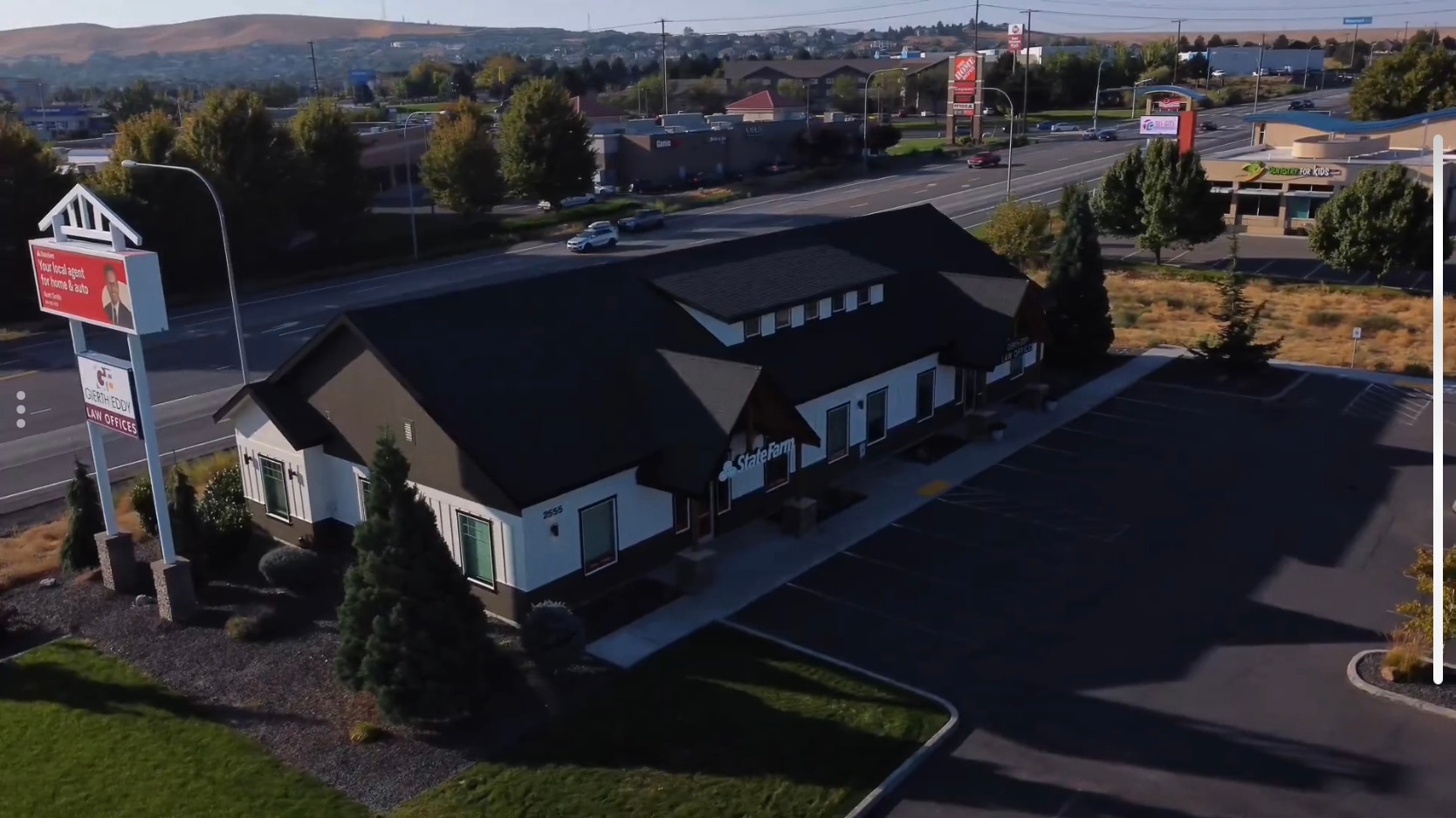 Restaurant building with a dark roof and sign by a road.