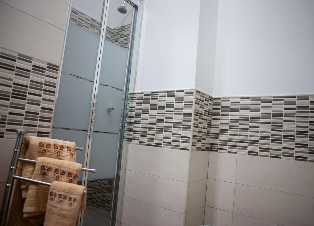 Bagno con specchio, pareti piastrellate e un appendiabiti in metallo con asciugamani e cesti intrecciati.