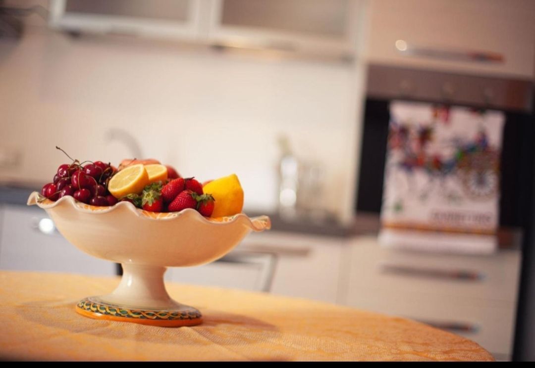 Ciotola da dessert ripiena di frutta su un tavolo di legno in cucina, con frutti di bosco e fette di pesca.