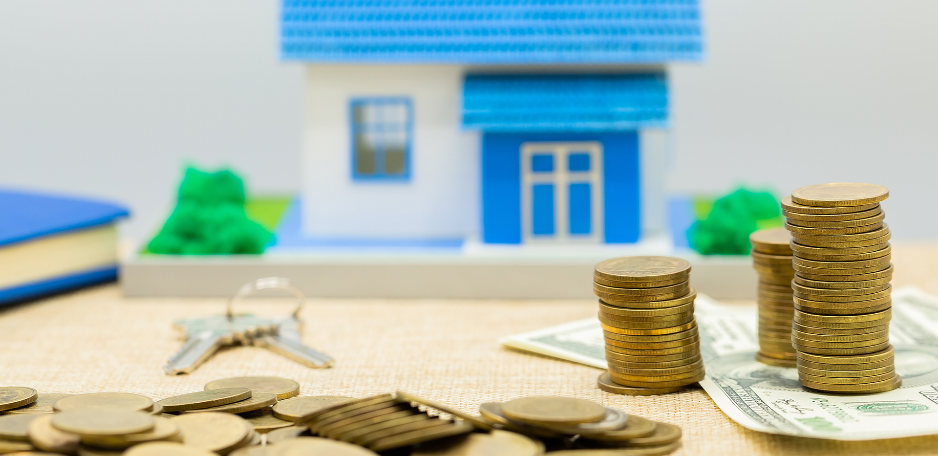 there are stacks of coins and money on the table in front of a model house .