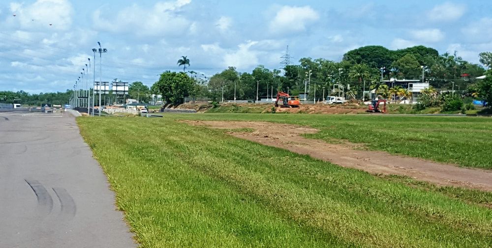 A Grassy Field Next to a Road With Trees in the Background — Diggamen Civil Contracting in Tivendale, NT