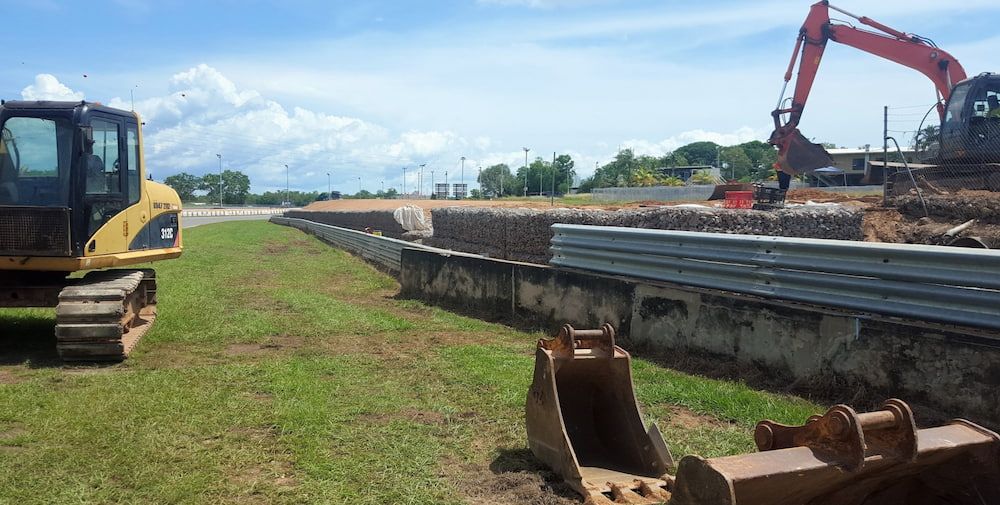 A Construction Site With a Yellow Excavator and a Red Excavator — Diggamen Civil Contracting in Tivendale, NT