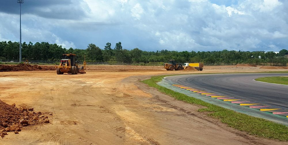 Two Bulldozers Are Working on a Dirt Road Next to a Race Track — Diggamen Civil Contracting in Tivendale, NT