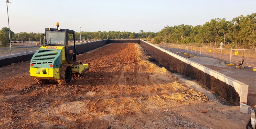 A Yellow and Green Bulldozer is Moving Dirt on a Construction Site — Diggamen Civil Contracting in Tivendale, NT