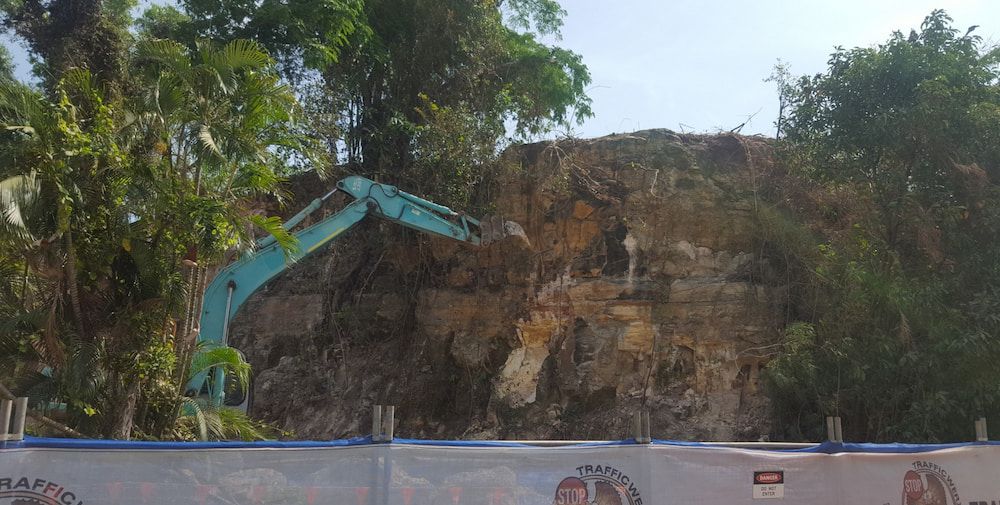 A Large Blue Excavator is Sitting in Front of a Fence — Diggamen Civil Contracting in Tivendale, NT