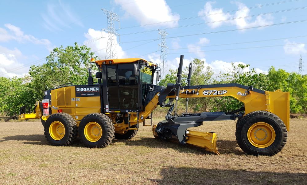 A Yellow Tractor is Parked in a Field With Trees in the Background — Diggamen Civil Contracting in Tivendale, NT