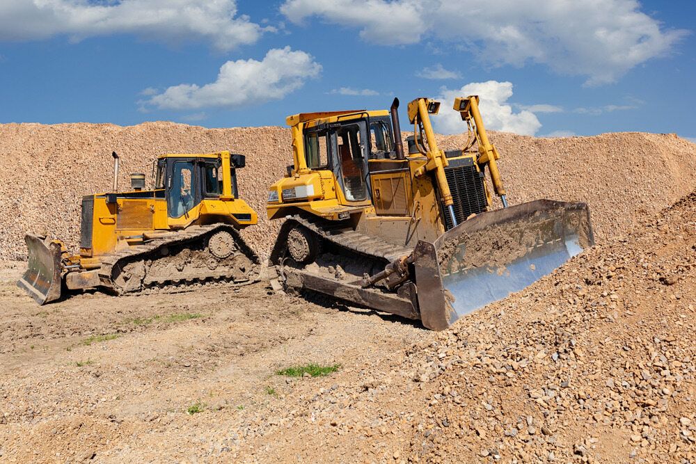 two yellow bulldozers are pushing dirt around — Diggamen Civil Contracting in Tivendale, NT