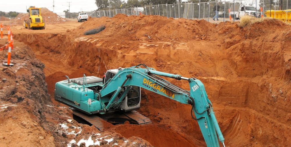 A Large Excavator is Digging a Hole in the Dirt — Diggamen Civil Contracting in Tivendale, NT