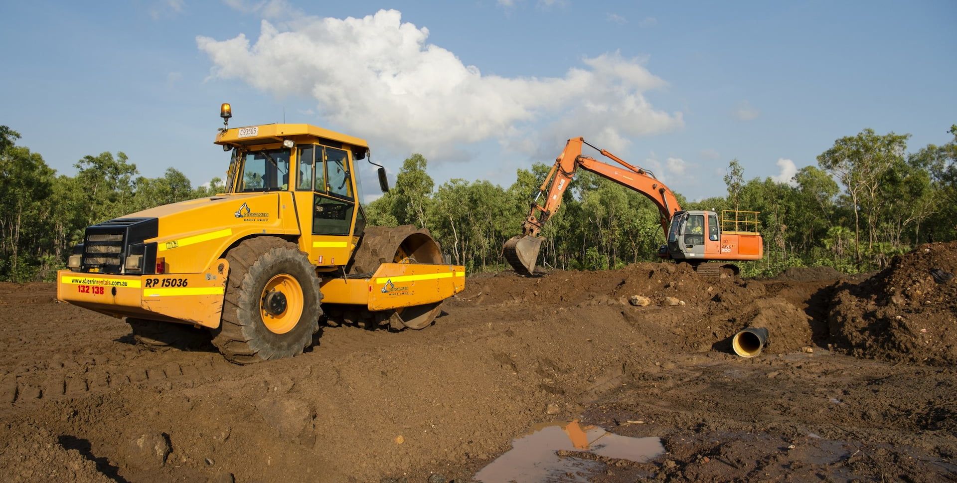 A Yellow Tractor and An Orange Excavator Are in A Dirt Field — Diggamen Civil Contracting in Humpty Doo, NT